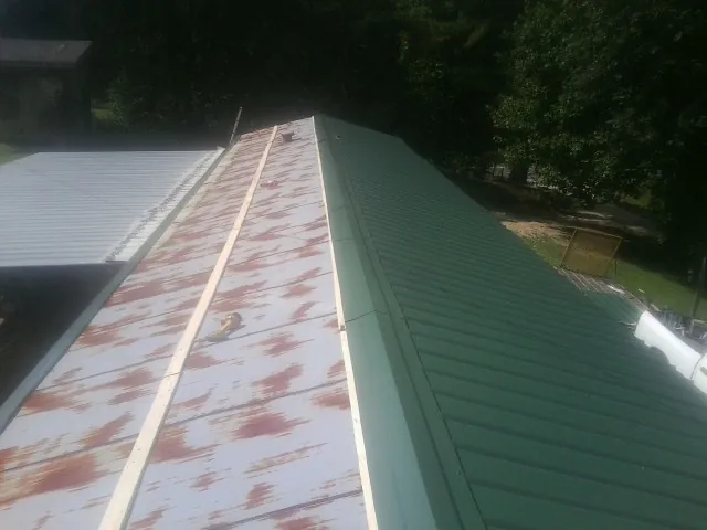 Old rusted panels beside newly installed green metal roofing — Wind Damage Roof Repair by Roofing Brothers in Cape Girardeau