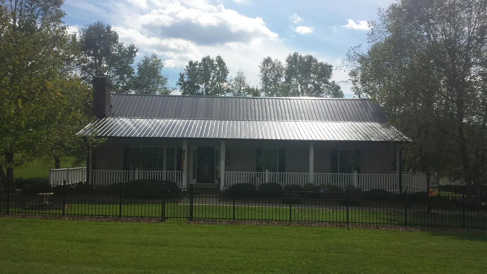 Gray metal roof on a brick ranch with a full width front porch — Gutter Guard Installation work by our crew in Cape Girardeau