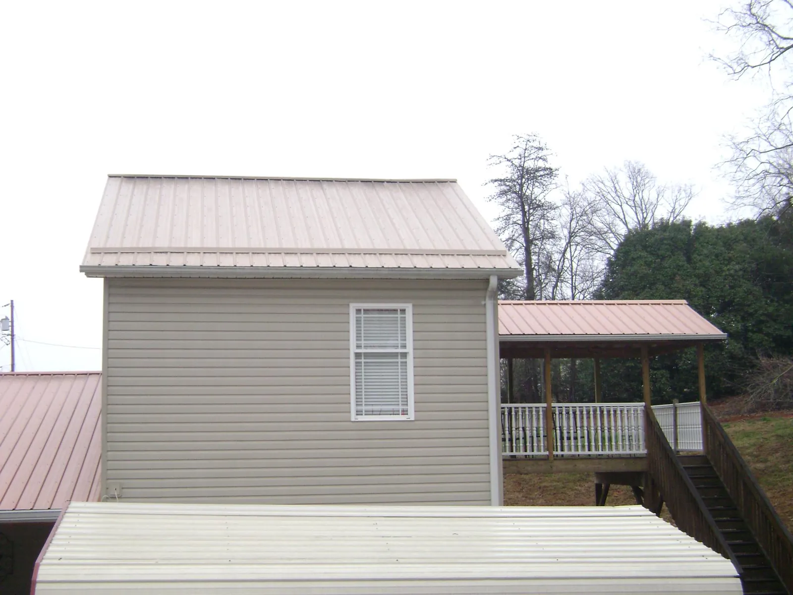 Tan metal roofs on a two story addition and attached porch, from a Roof Replacement job in Cape Girardeau