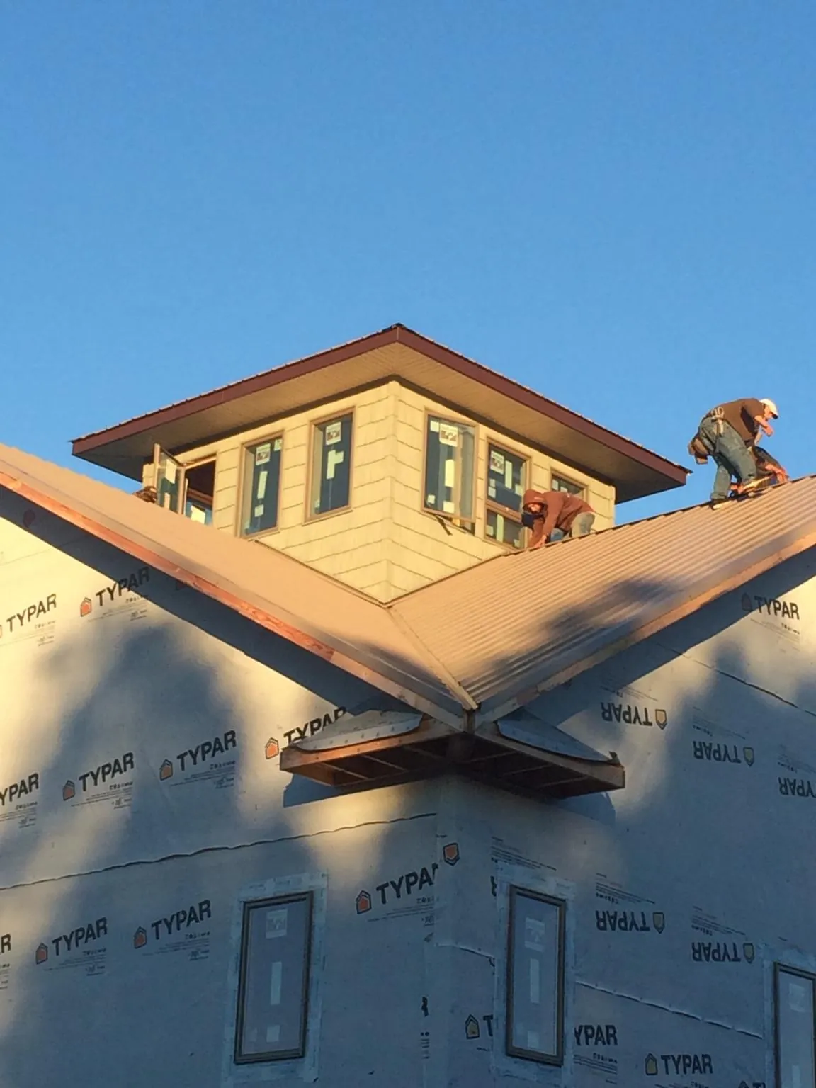 Roofers working around a rooftop cupola on a new metal roof at sunset — Roof Waterproofing in Cape Girardeau by Roofing Brothers
